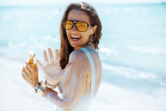femeie zambitoare la mare care are crema spf pe brat si in palma