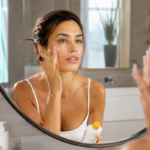 femeie care aplica spf 50 pe ten in oglinda